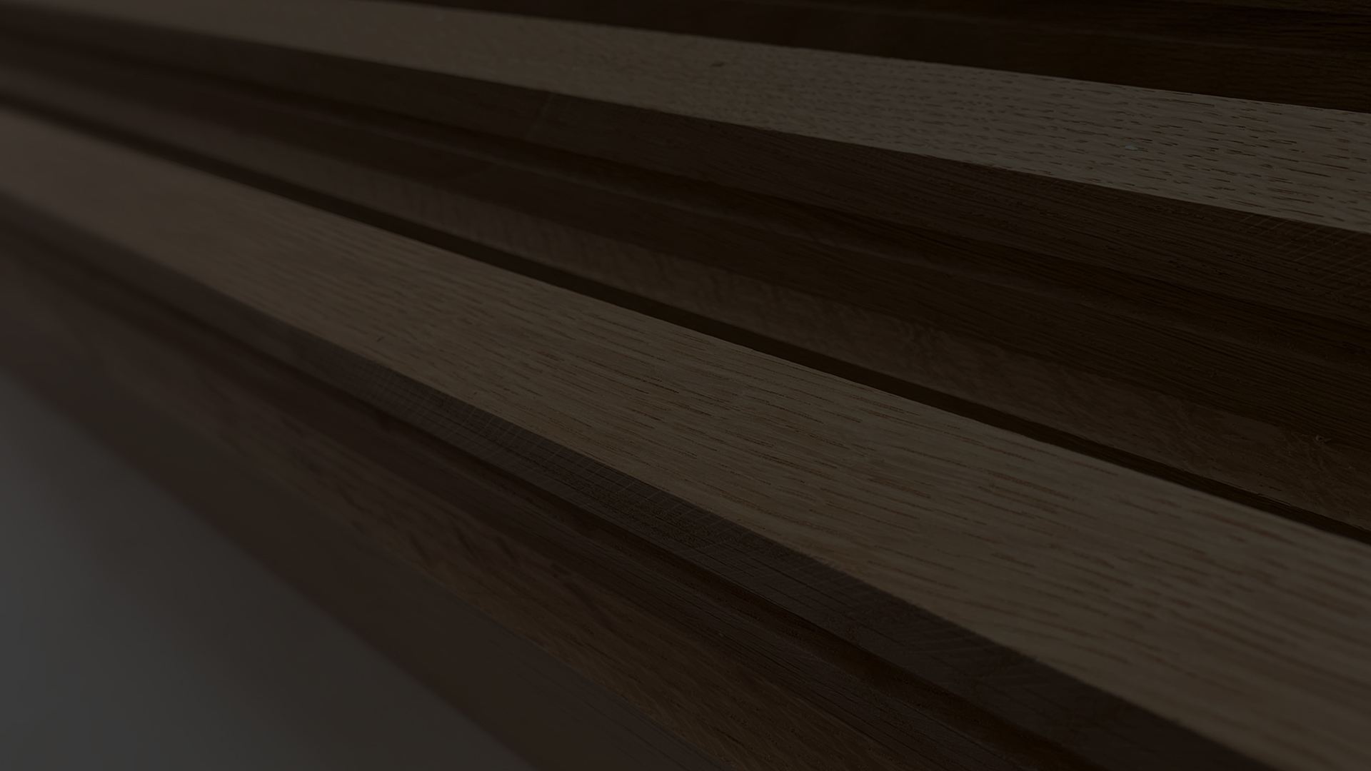 A dark sideways close-up of smooth machined pieces of oak timber on a table in the malek joinery workshop.