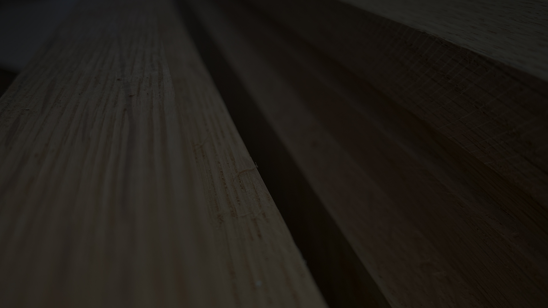 A dark straight-on close-up of smooth machined pieces of oak timber on a table with small imperfections in the malek joinery workshop.