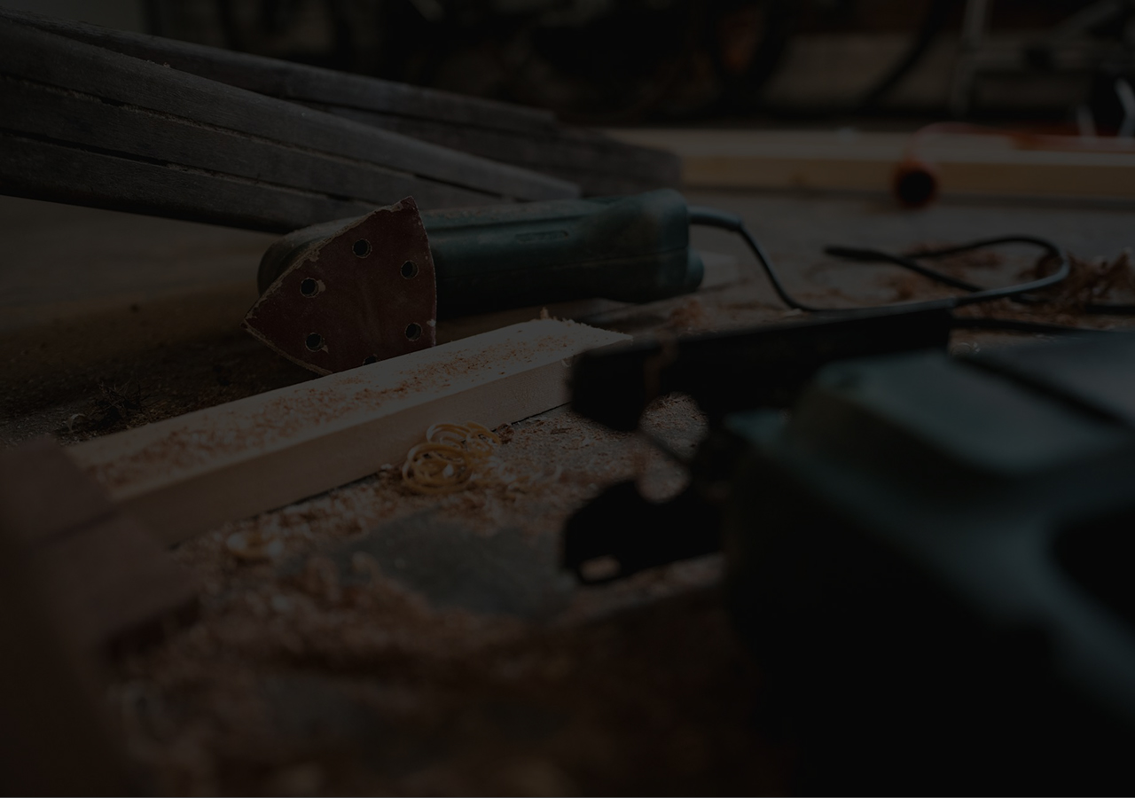 A workbench with wood shavings, pine timber, a sanding multi-tool, and a jigsaw.