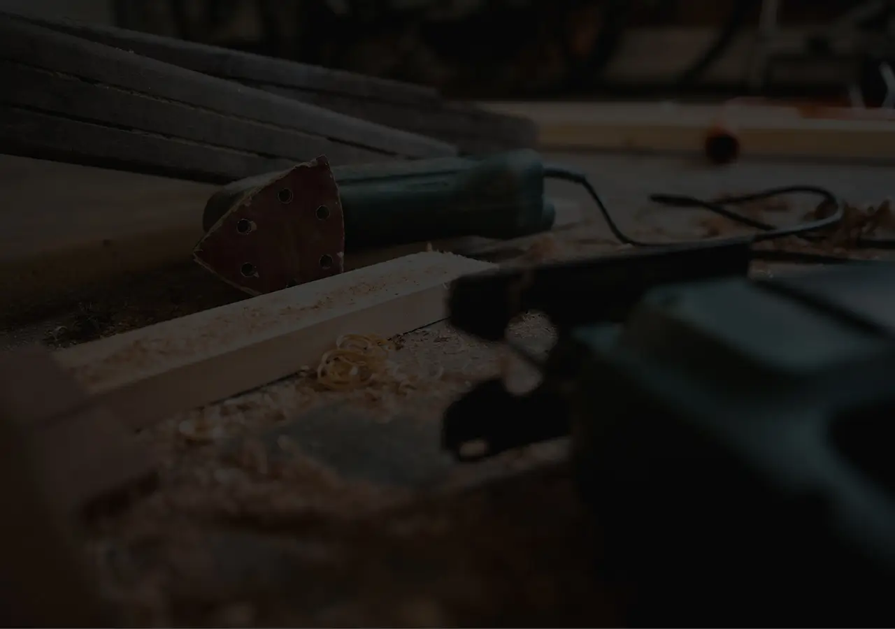 A workbench with wood shavings, pine timber, a sanding multi-tool, and a jigsaw.